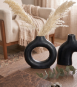 Double black ceramic vase with dried pampas grass and dark botanicals on wooden shelf