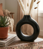 Ceramic hollow ring flower pot with trailing pothos plant cascading through the ring on a wooden shelf