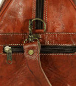 Close-up of handmade Moroccan kilim travel bag showing traditional handwoven Berber carpet fabric panel with diamond geometric pattern in rust cream and terracotta natural wool