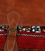 Close-up of handmade Moroccan kilim travel bag showing traditional handwoven Berber carpet fabric panel with diamond geometric pattern in rust cream and terracotta natural wool