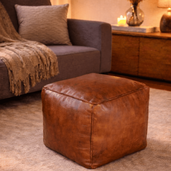 Moroccan Cognac Leather Ottoman Pouf In Warm Living Room Beside Navy Sofa With Brass Tray On Top, Handcrafted Genuine Leather With Traditional Embroidery Morocco