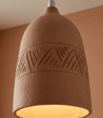 Three handmade terracotta pendant lights hanging in a row over a white kitchen island in a minimalist interior