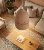 Single minimalist clay hanging lamp suspended low over round dining table with linen napkins and candles